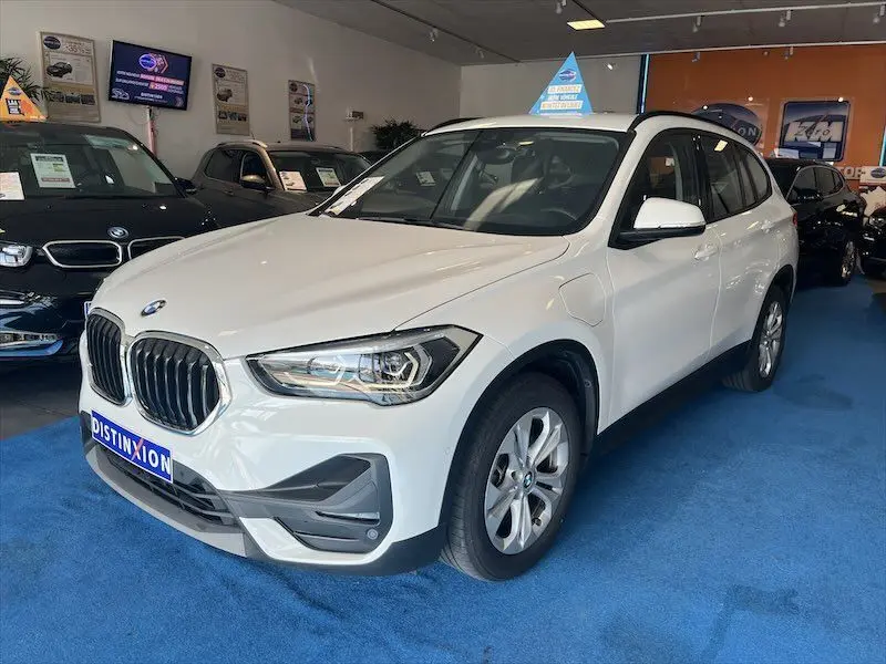 BMW X1 XDRIVE blanc alpin vu en 3/4 avant droit dans un showroom avec détails de calandre et phares LED visibles