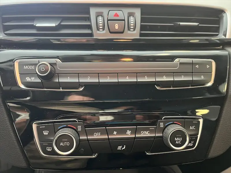 Tableau de bord noir de BMW X1 XDRIVE 25E 220CH 2021, vue frontale sur commandes climatisation et radio.