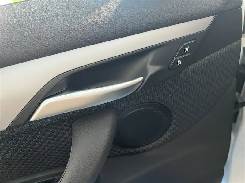 Gros plan sur la poignée intérieure côté gauche de la porte d'une BMW X1 XDRIVE blanc alpin avec boutons de verrouillage.