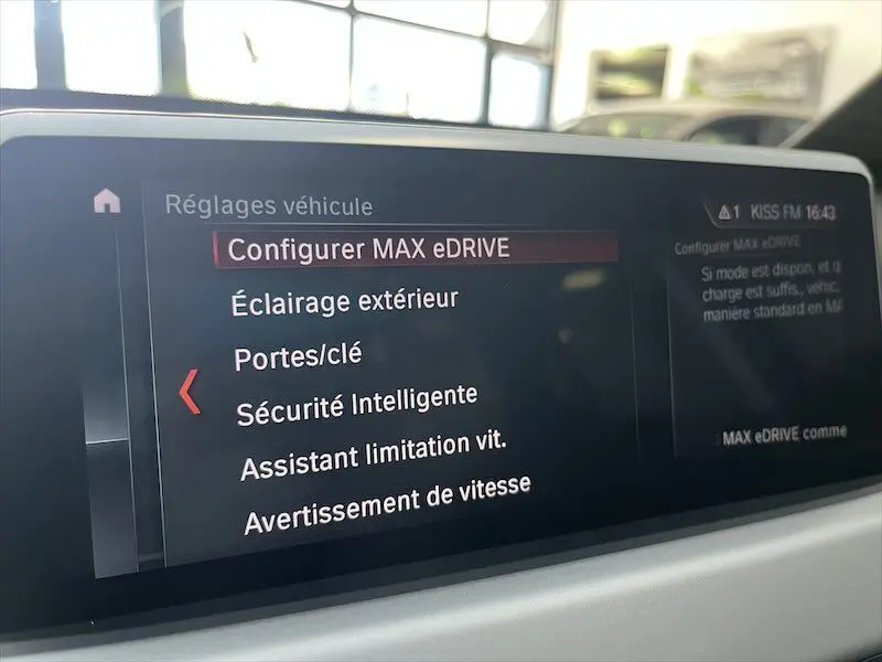 Écran central du BMW X1 XDRIVE 25E 220CH affichant les réglages de conduite et sécurité en intérieur lumineux.