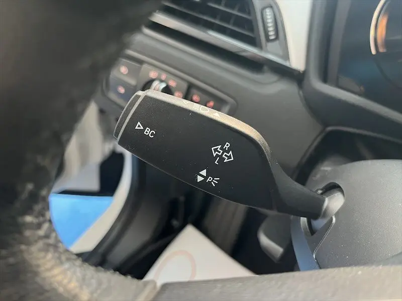 Gros plan sur la commande de clignotant à gauche du volant dans l'habitacle d'un BMW X1 blanc alpin 2021 hybride rechargeable.