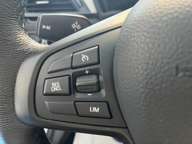 Gros plan sur les commandes de régulateur de vitesse au volant noir d'un BMW X1 XDRIVE blanc alpin.