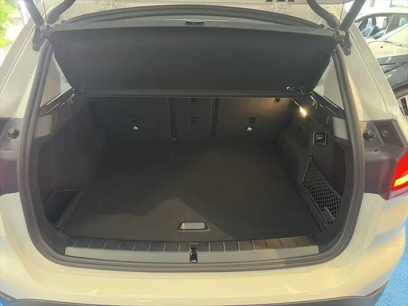 Coffre ouvert vu de l'arrière d'un BMW X1 XDRIVE blanc alpin, montrant un espace de chargement spacieux et propre.