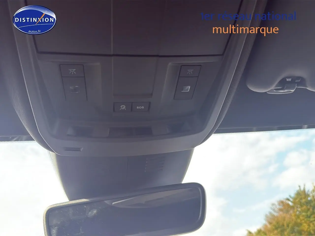 Vue intérieure du plafond avant du Peugeot 3008 gris titane, montrant les commandes d'éclairage et le bouton SOS au-dessus du rétroviseur central.