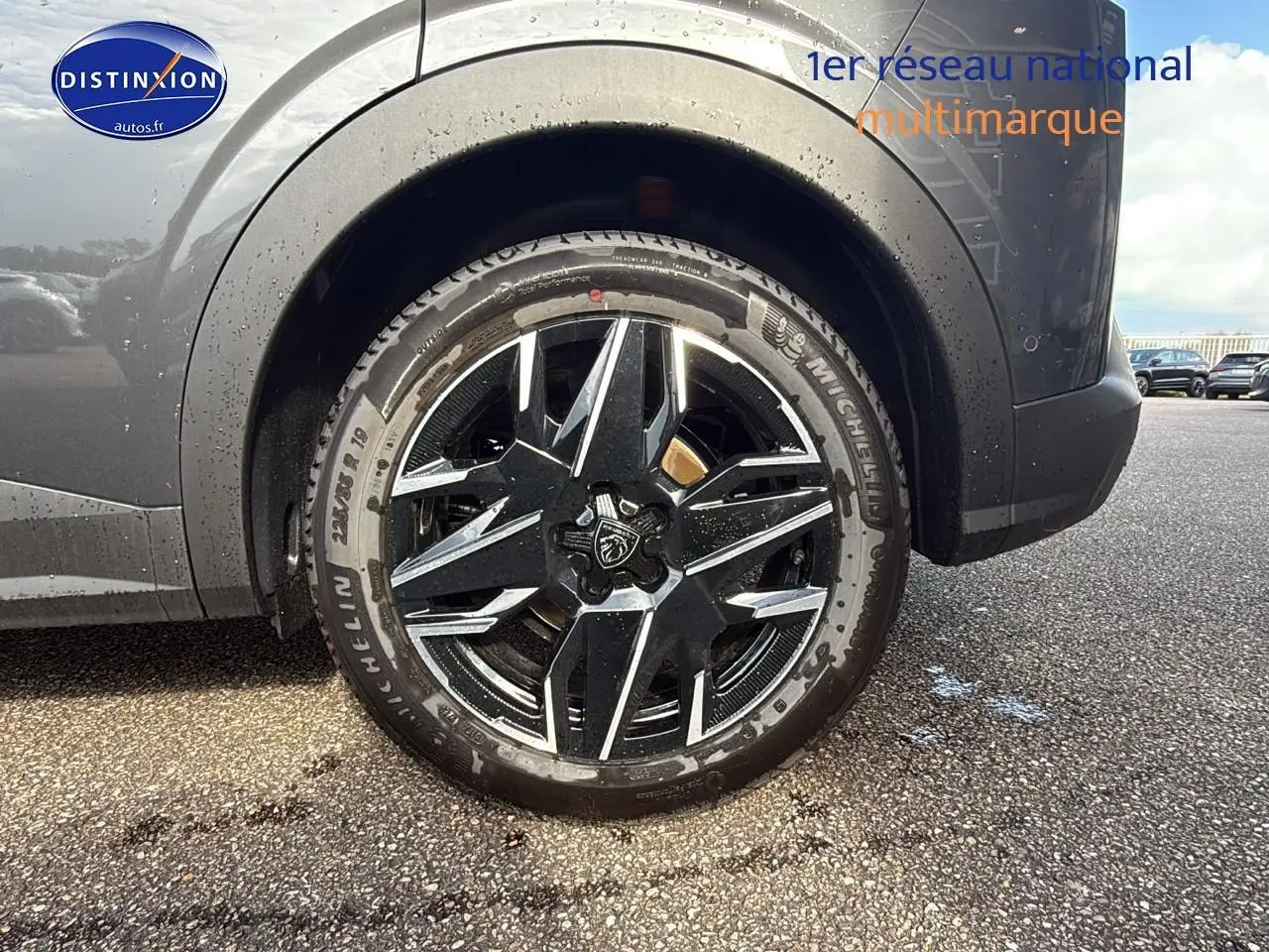 Gros plan sur la roue arrière droite du Peugeot 3008 gris titane avec jante alu noire et argentée design étoilé.