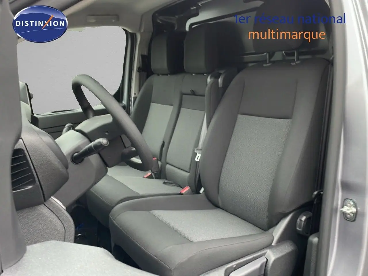 Intérieur du Citroën Jumpy 2025 en gris, vue côté conducteur montrant les sièges tissu bicolore et le volant multifonction.