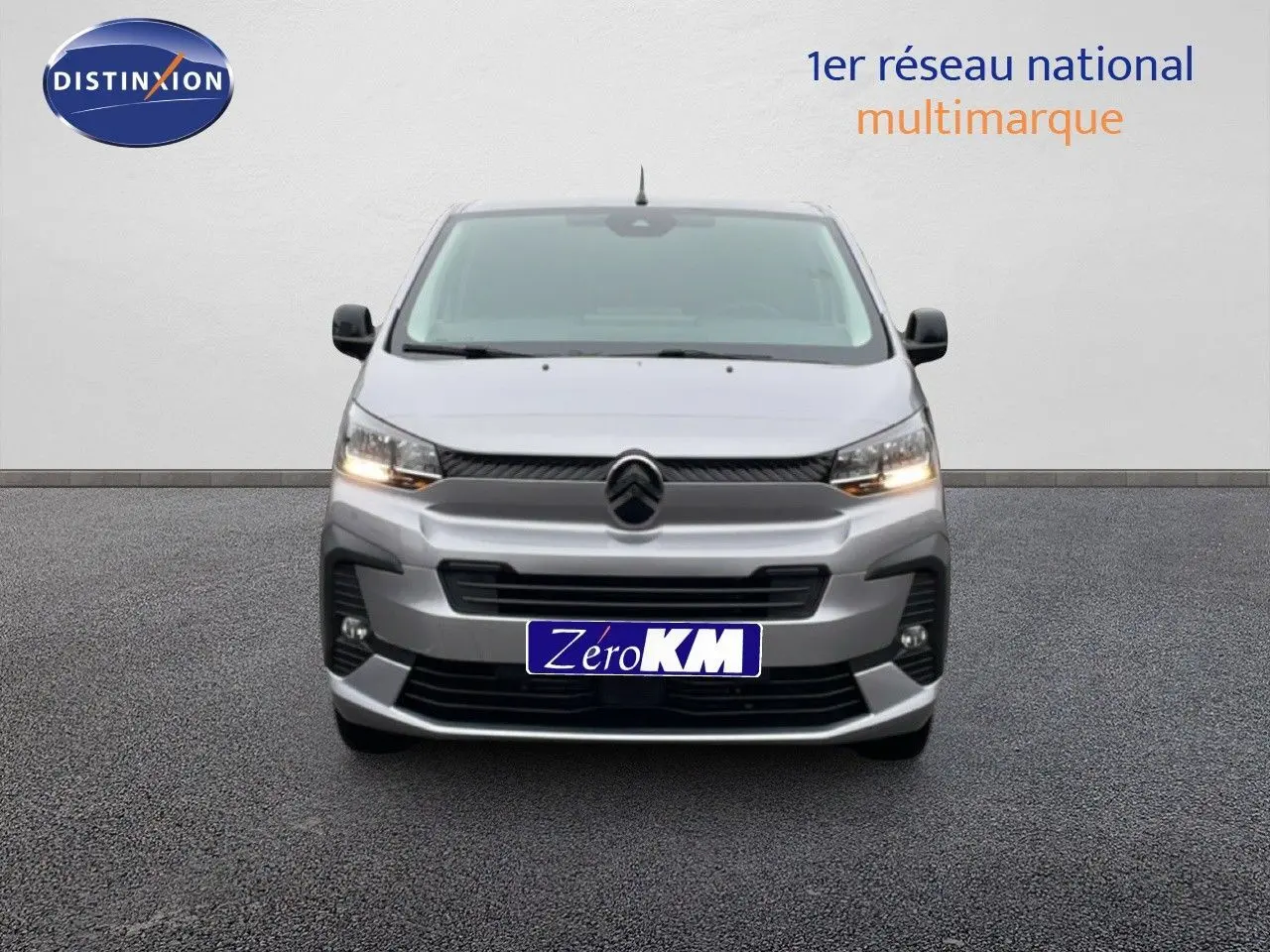 Vue frontale d'un Citroën Jumpy gris Artense Metal avec calandre noire et feux allumés sur fond neutre.