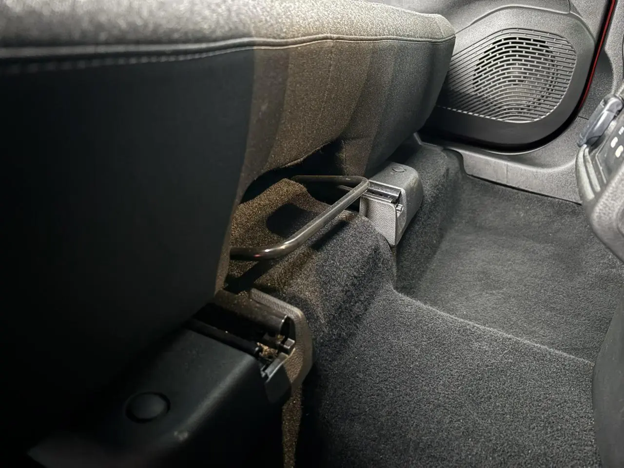 Vue rapprochée de l’espace pieds avant droit du Renault Captur 2025, moquette noire et enceinte de porte visible.