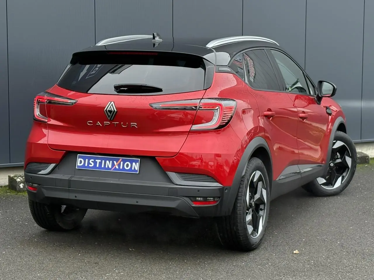 Renault Captur 2025 rouge flamme et toit noir, vue 3/4 arrière droit avec jantes alu noires diamantées.