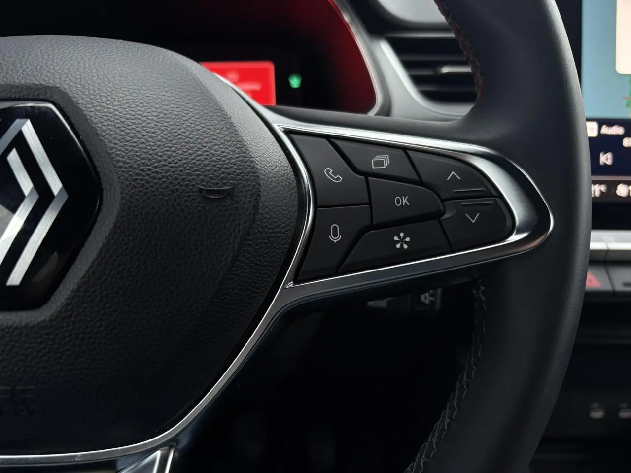 Gros plan sur les commandes à droite du volant noir du Renault Captur 2025 avec logo chromé au centre.