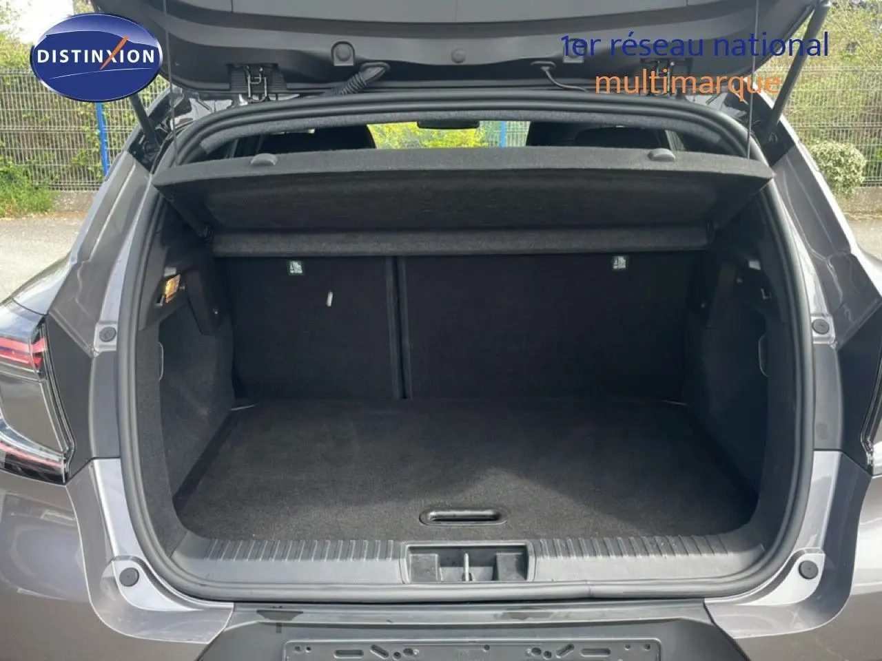 Coffre ouvert vu de l’arrière d’un Renault Captur gris Cassiopée métal avec toit noir, montrant l’espace de chargement vide.