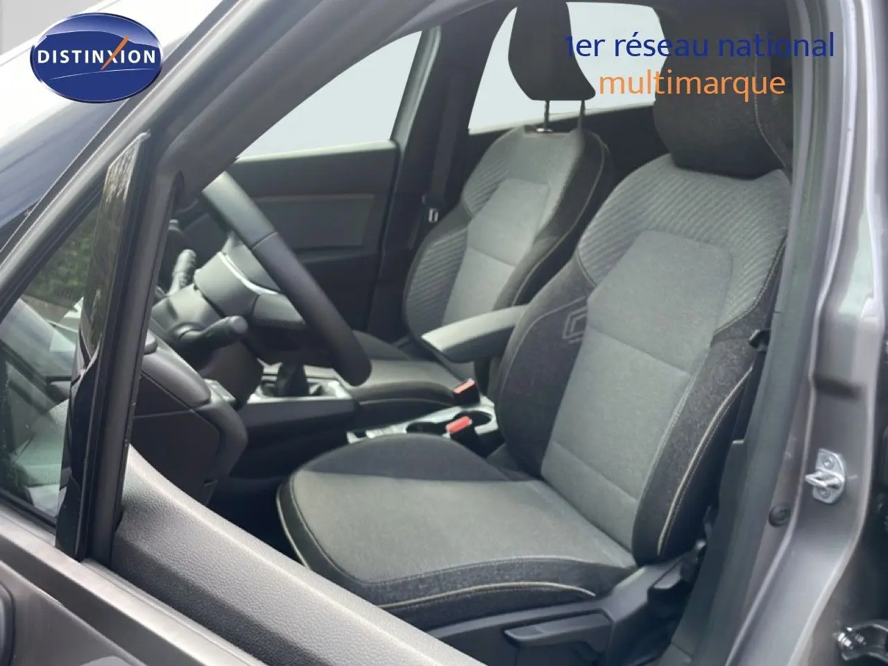 Vue intérieure côté conducteur du Renault Captur gris Cassiopée avec sièges tissu gris et volant noir.