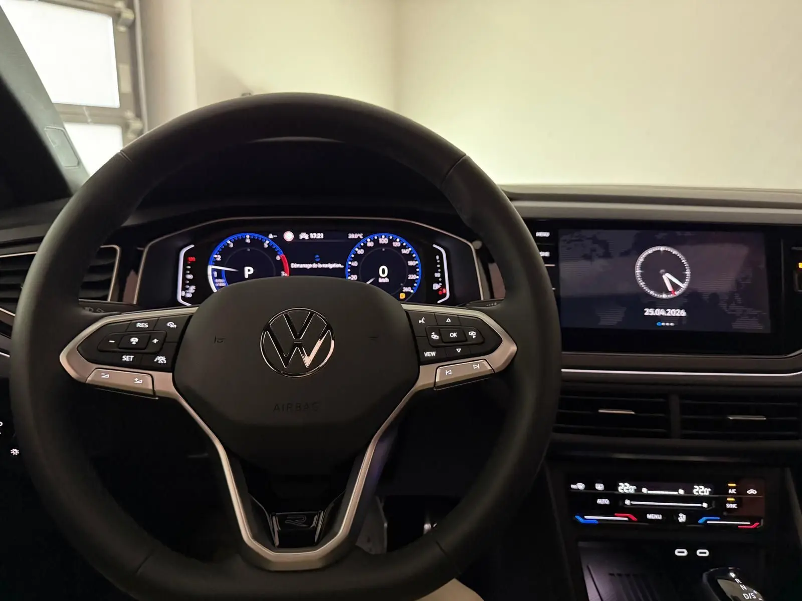 Vue intérieure centrée sur le volant multifonctions Volkswagen avec tableau de bord digital et écran tactile noir.