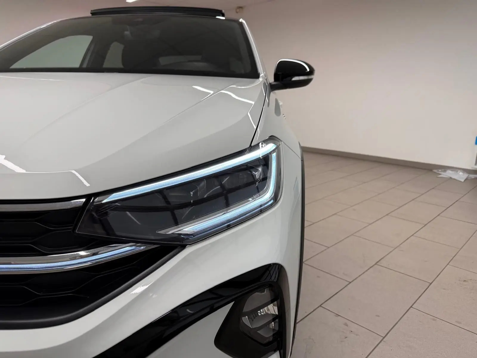 Gros plan sur l'avant droit du Volkswagen Taigo blanc pur avec projecteur Matrix LED et calandre noire.