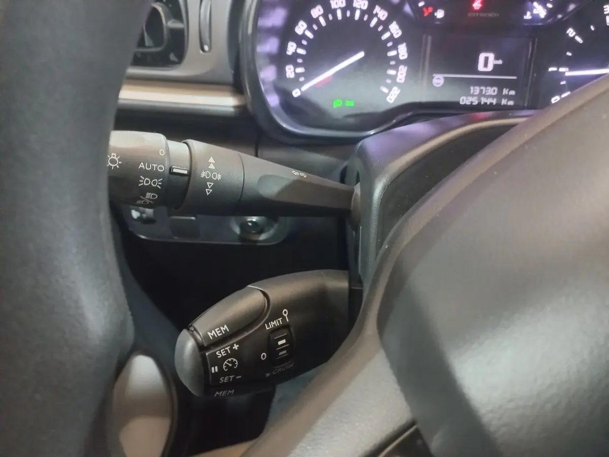 Vue rapprochée du tableau de bord de la Citroën C3 2024, montrant le volant noir et les commandes de régulateur de vitesse.