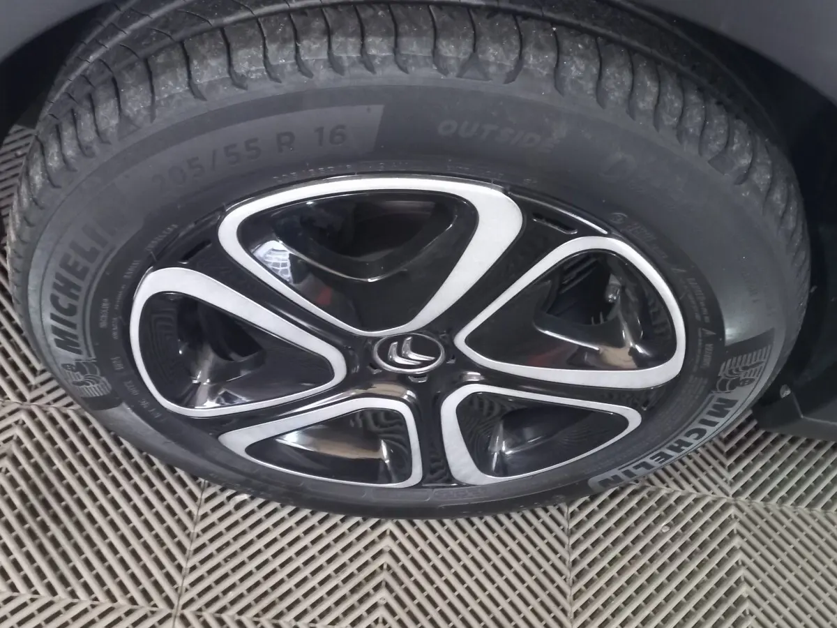 Gros plan sur la roue avant droite d'une Citroën C3 noire 2024 avec jante alliage noire et argentée au design moderne.