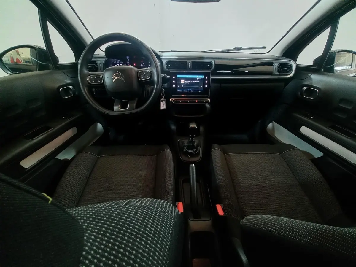 Vue intérieure avant de la Citroën C3 noire 2024, volant multifonctions, écran tactile central et boîte manuelle visible.