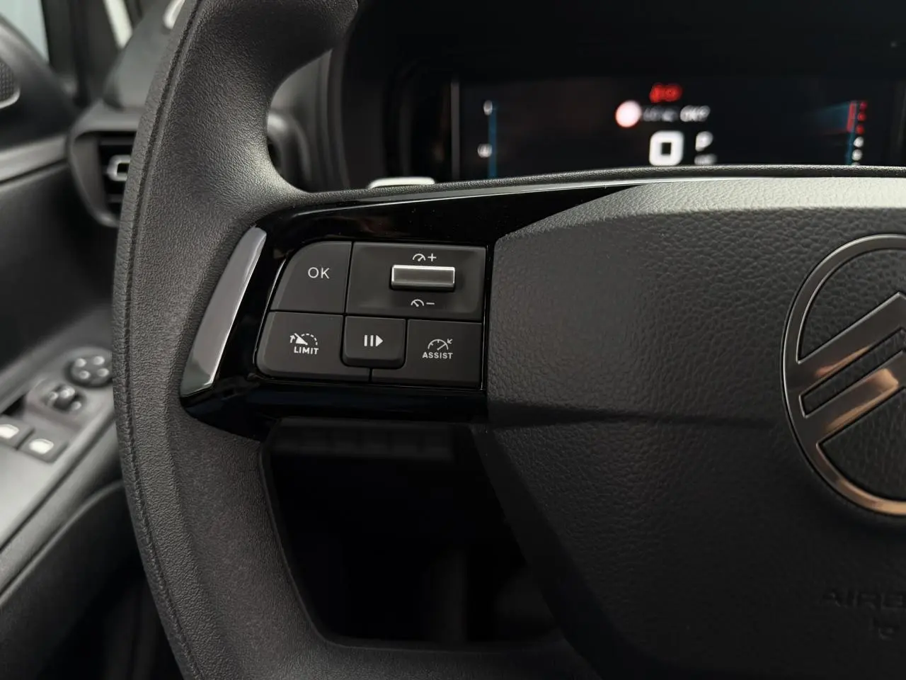 Gros plan sur le volant noir du Citroën Berlingo 2026, avec commandes multifonctions à gauche et logo central chromé.