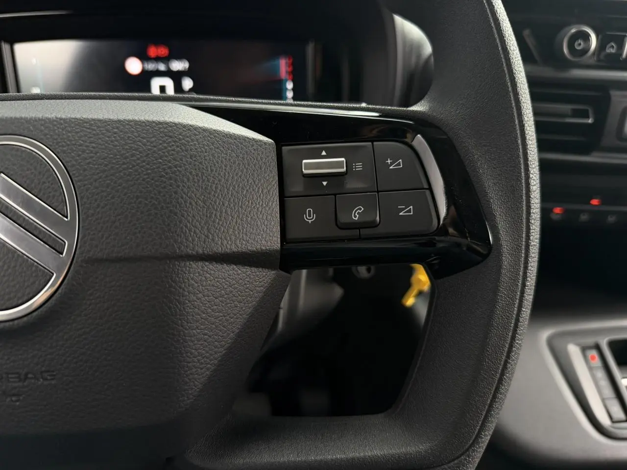 Gros plan sur les commandes du volant noir du Citroën Berlingo 2026, avec boutons multifonctions et tableau de bord flou en arrière-plan.
