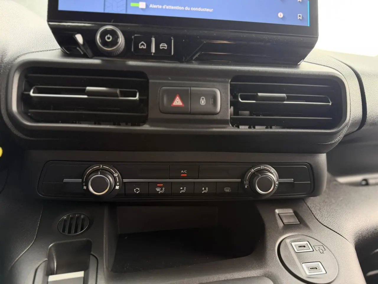 Vue rapprochée du tableau de bord noir du Citroën Berlingo 2026, avec commandes climatisation et écran tactile visible.