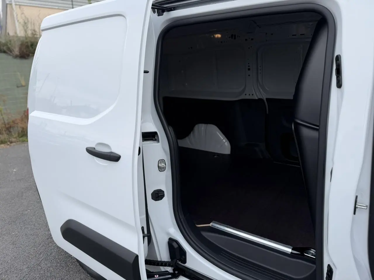 Vue côté droit du Citroën Berlingo Van XL blanc Icy avec porte latérale ouverte et plancher bois visible.