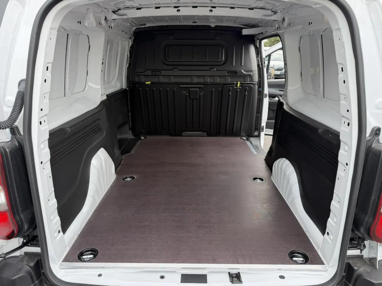 Vue arrière du Citroën Berlingo blanc Icy avec plancher bois antidérapant dans l’espace de chargement vide.