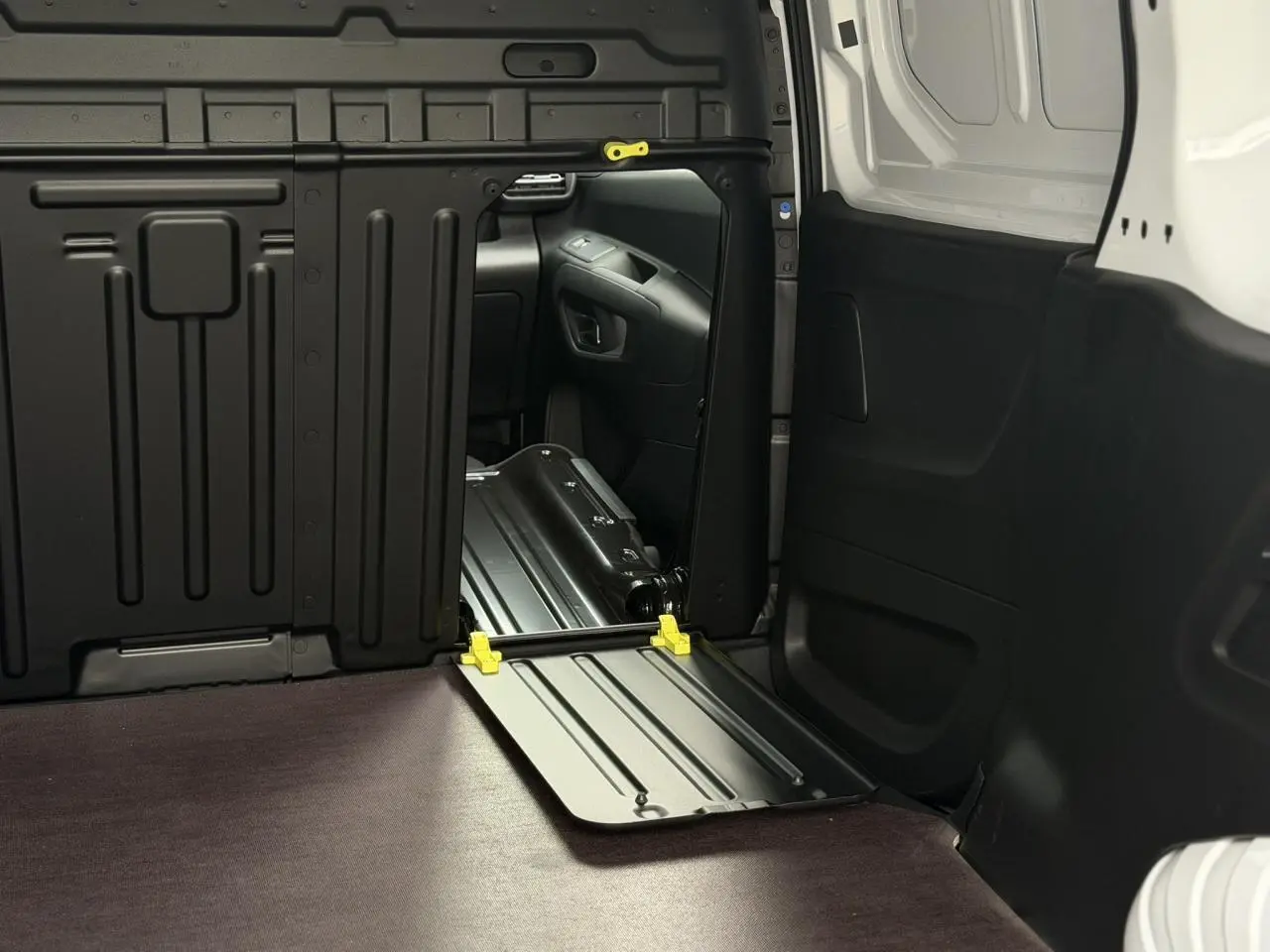 Vue intérieure du coffre du Citroën Berlingo Van XL blanc Icy, avec plancher bois et cloison tôlée noire.