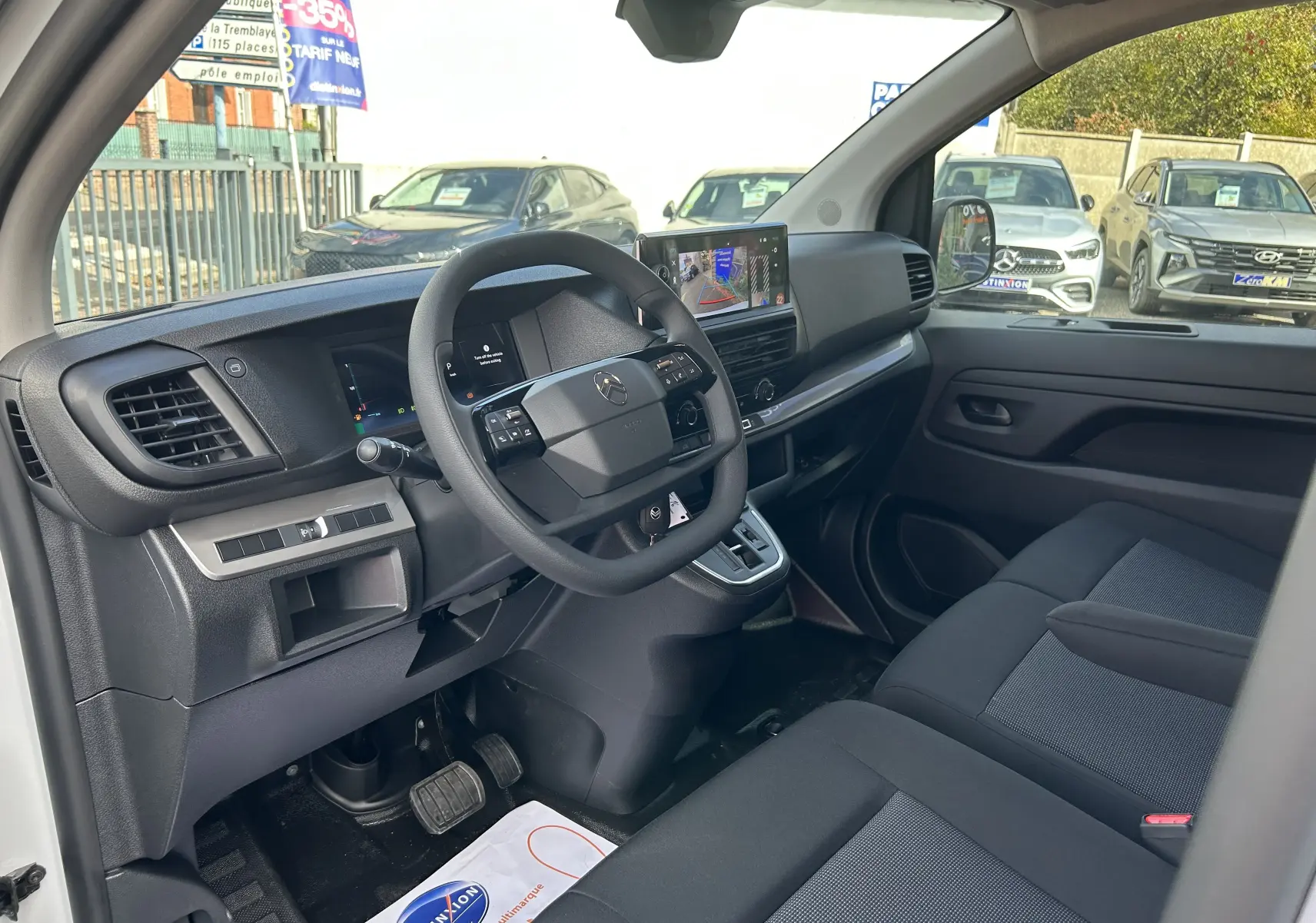 Intérieur du Citroën Jumpy Fourgon blanc 2025, vue côté conducteur montrant tableau de bord et sièges tissu noirs.