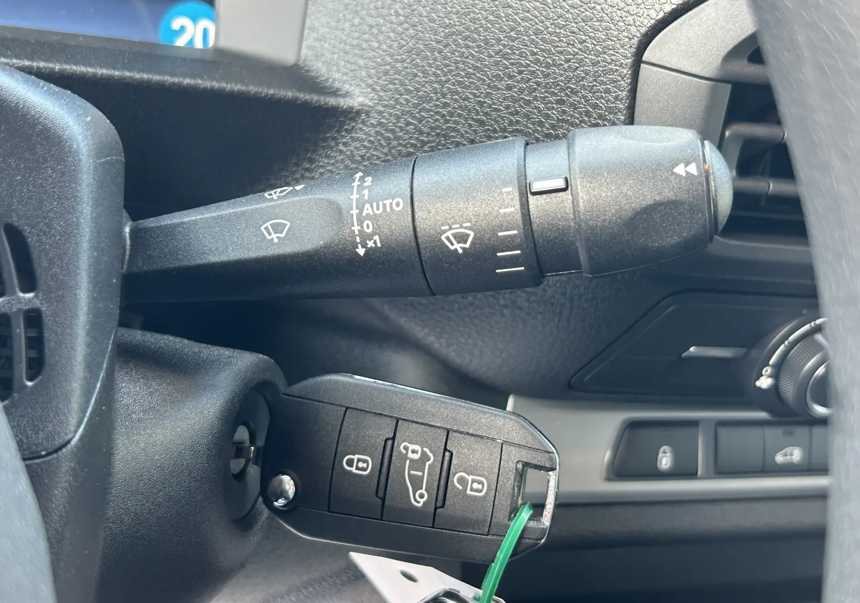 Gros plan sur la clé insérée dans le contacteur d'un Citroën Jumpy Fourgon blanc, avec commandes de l'essuie-glace visibles.