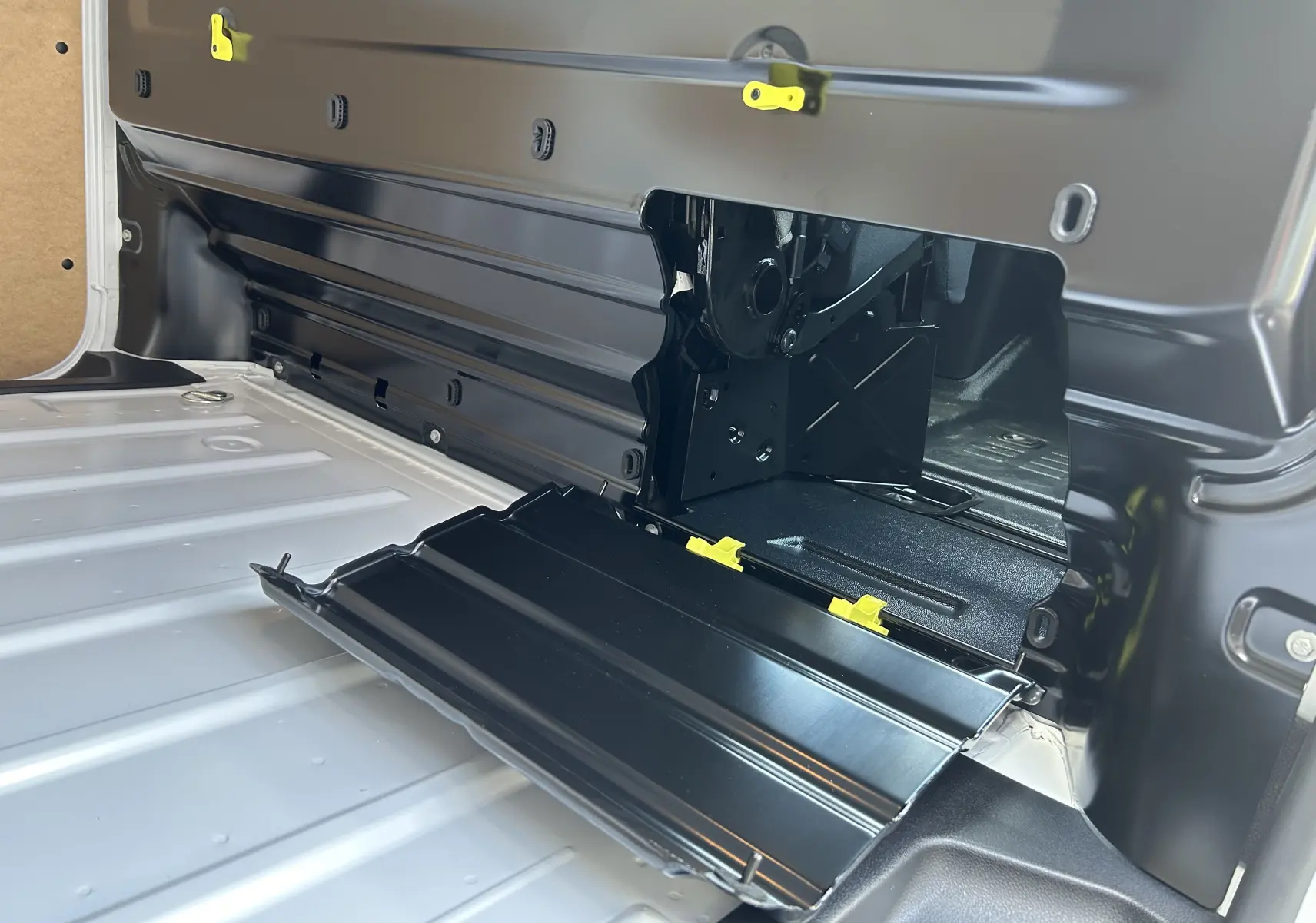 Détail intérieur du plancher blanc du Citroën Jumpy Fourgon 2025 avec trappe d'accès noire ouverte et fixations jaunes visibles.