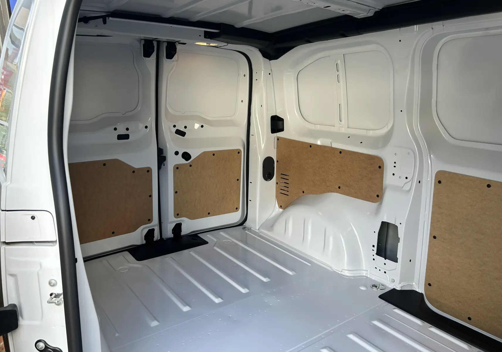 Intérieur du fourgon Citroën Jumpy Ph.2 blanc vu de l'arrière, montrant la zone de chargement avec panneaux en bois.