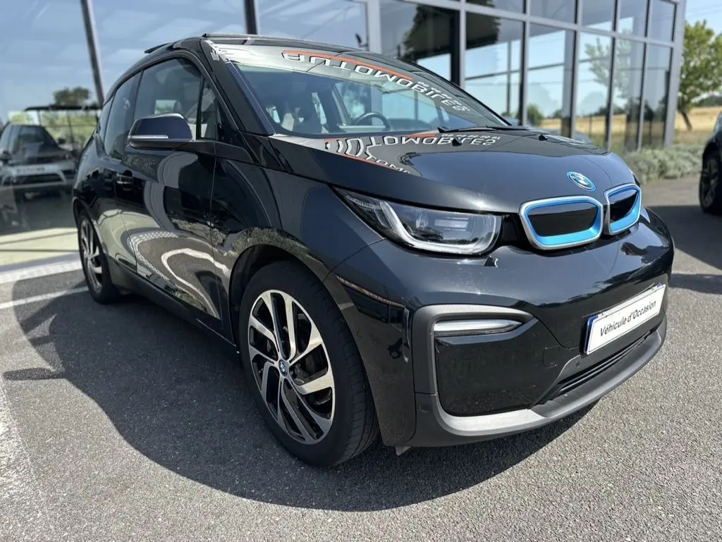 BMW i3 noire électrique vue en 3/4 avant droit, avec calandre bleutée et jantes distinctives en alliage.