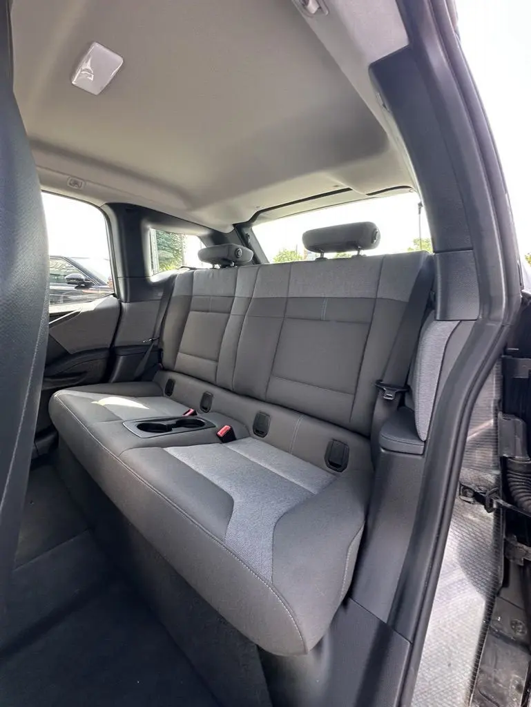 Vue intérieure côté droit des sièges arrière gris clair et foncé d'une BMW i3 noire électrique 2022 avec porte ouverte.