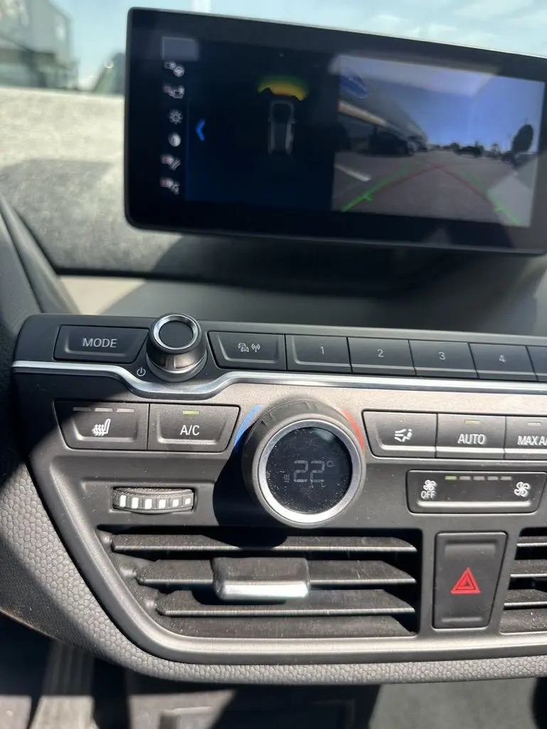 Vue rapprochée du tableau de bord noir de la BMW i3 2022 avec écran multimédia et commandes de climatisation digitales.
