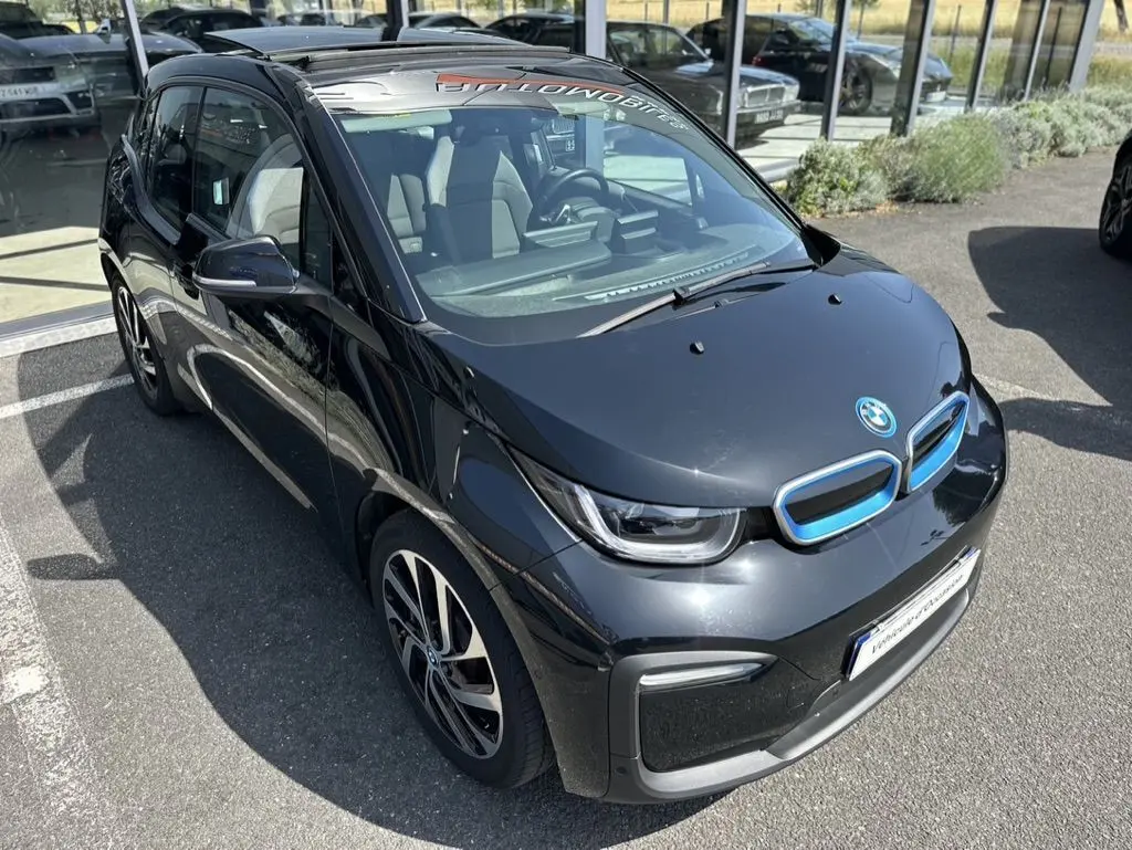 Vue 3/4 avant droite d'une BMW i3 noire électrique 2022 avec calandre bleue distinctive et jantes stylisées.