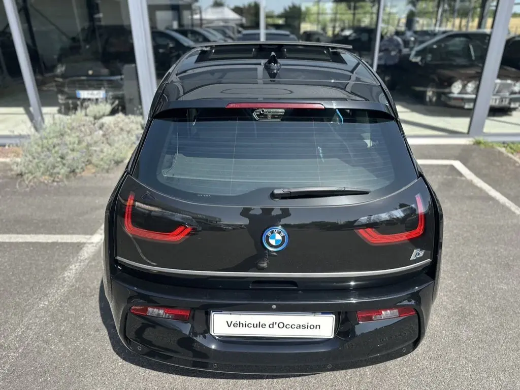 Vue arrière d'une BMW i3 noire 2022 avec feux LED distinctifs et logo centré, stationnée devant un showroom.