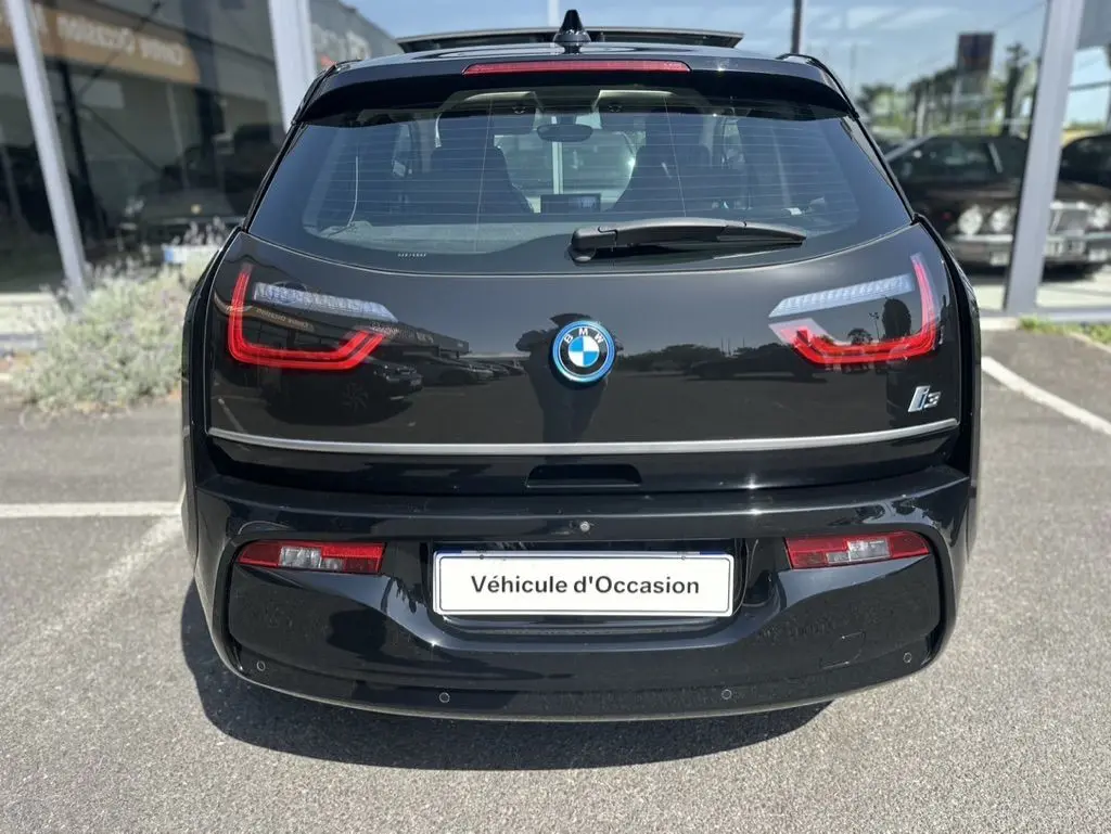 Vue arrière d'une BMW i3 noire électrique 2022 avec feux LED distinctifs et logo central sur un parking.