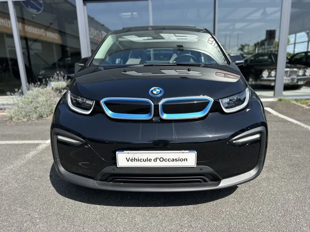 Vue frontale d'une BMW i3 noire 2022 avec calandre bleutée et plaque "Véhicule d'Occasion" en concession.