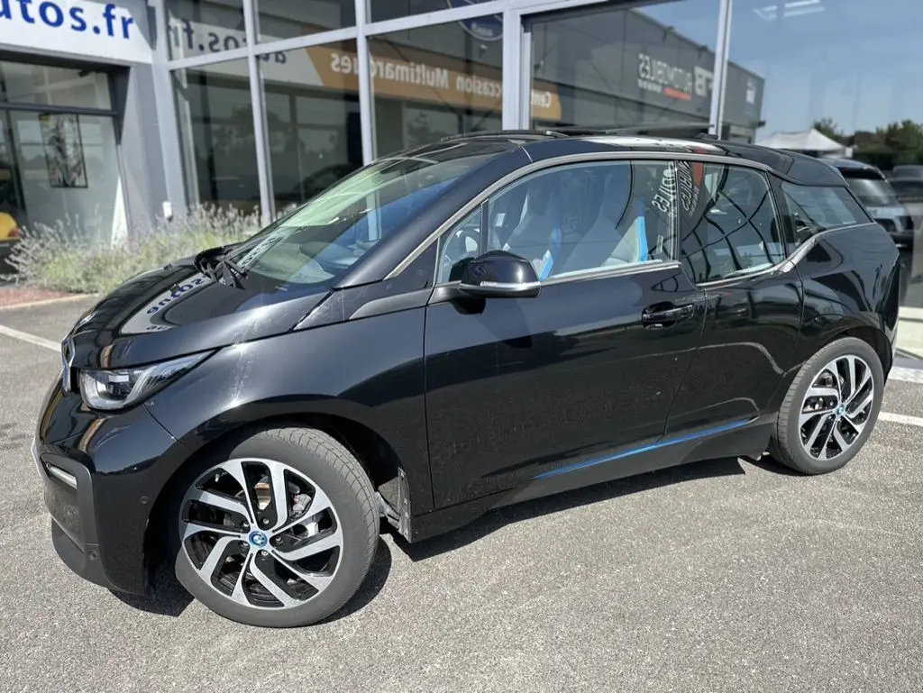 BMW i3 noire vue de profil côté gauche, mettant en valeur ses jantes distinctives et son design compact électrique.