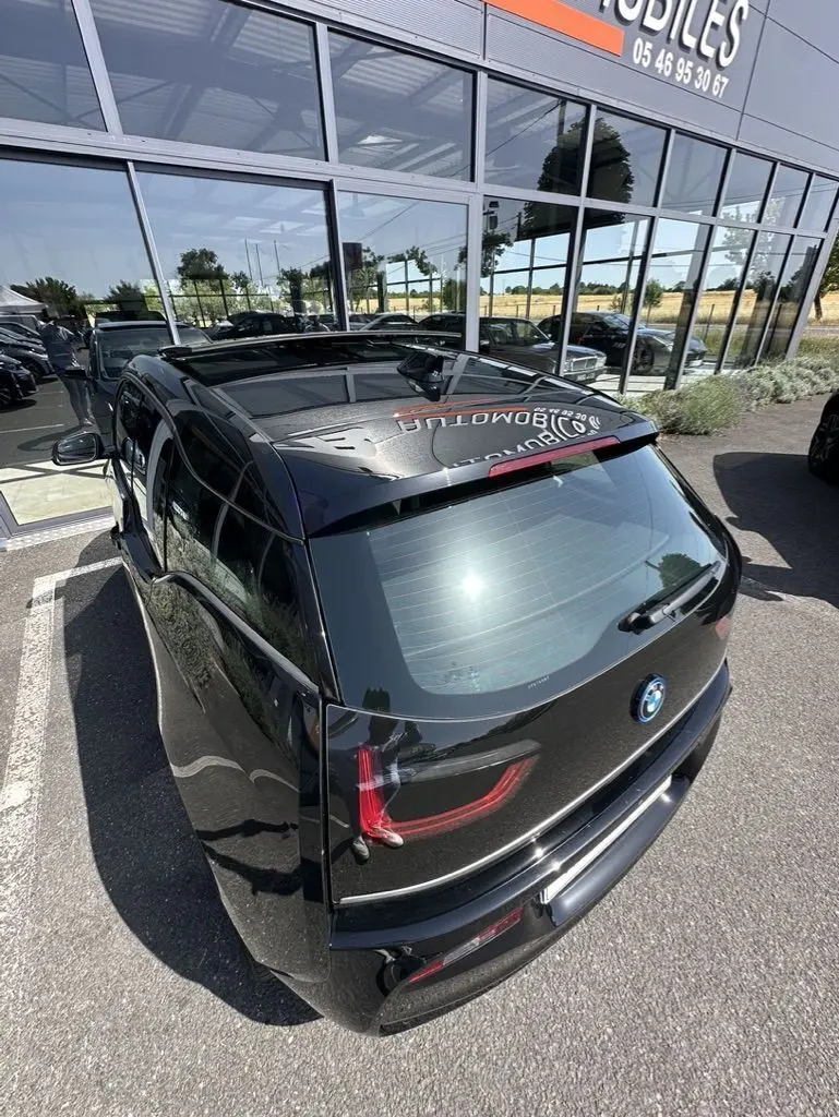Vue 3/4 arrière d'une BMW i3 noire électrique 2022, avec feux arrière LED et toit panoramique visible.