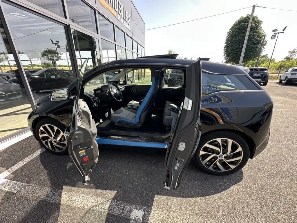 BMW i3 noire 2022 vue de profil droit avec portes ouvertes dévoilant l'intérieur aux sièges bleu et noir.