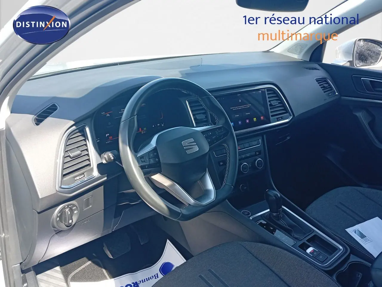 Intérieur du SEAT Ateca 2023 vu côté conducteur, tableau de bord noir avec écran tactile et volant multifonction.