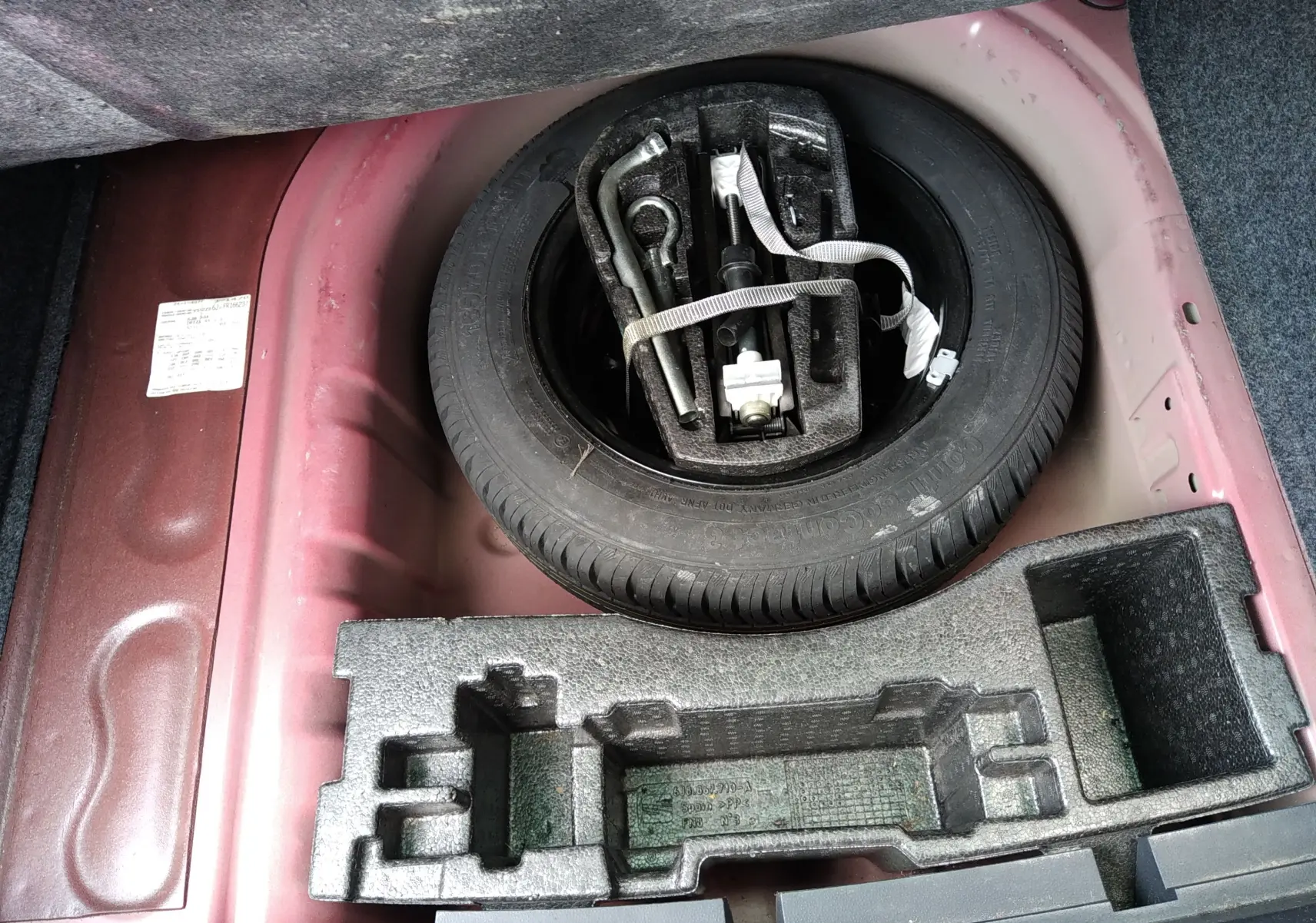 Vue rapprochée sur la roue de secours et les outils dans le coffre rouge d’une SEAT IBIZA ST 2015.