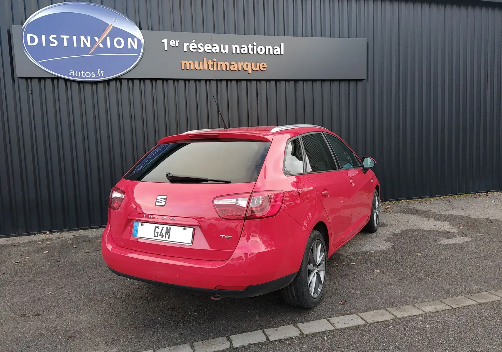 Vue 3/4 arrière droite d'une SEAT Ibiza ST rouge de 2015, avec feux arrière et logo SEAT bien visibles.
