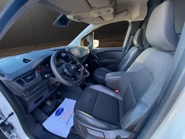 Vue intérieure côté conducteur du Renault Kangoo blanc 2023, avec tableau de bord moderne et sièges tissu noir.