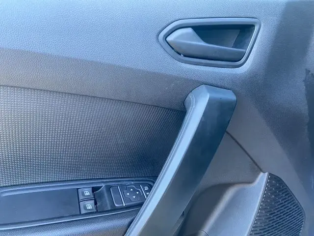 Gros plan sur la poignée intérieure et les commandes de fenêtre côté conducteur du Renault Kangoo 2023, finition noire.