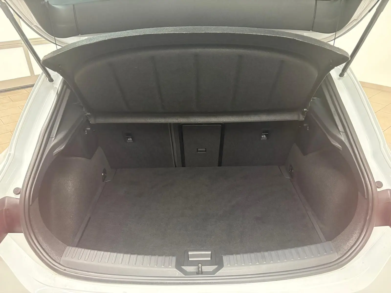 Coffre ouvert vu de l'arrière d'une CUPRA Leon blanc Nevada, montrant l'espace de chargement vide et la trappe arrière.