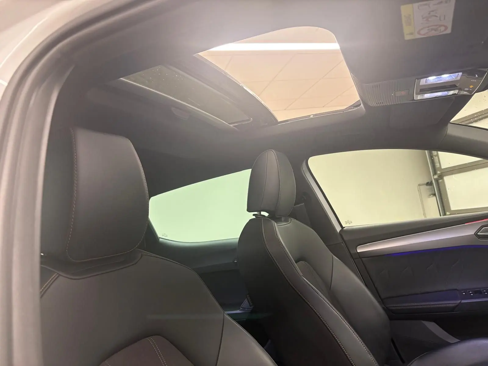 Vue intérieure côté droit montrant les sièges en cuir noir et le toit ouvrant panoramique de la CUPRA Leon 2024.