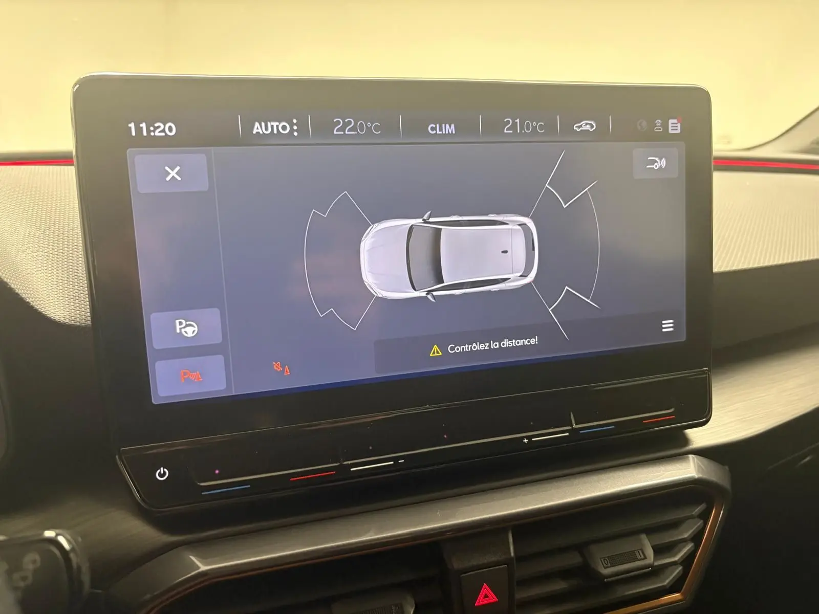 Écran tactile intérieur affichant l'aide au stationnement du CUPRA Leon blanc Nevada avec toit ouvrant panoramique.