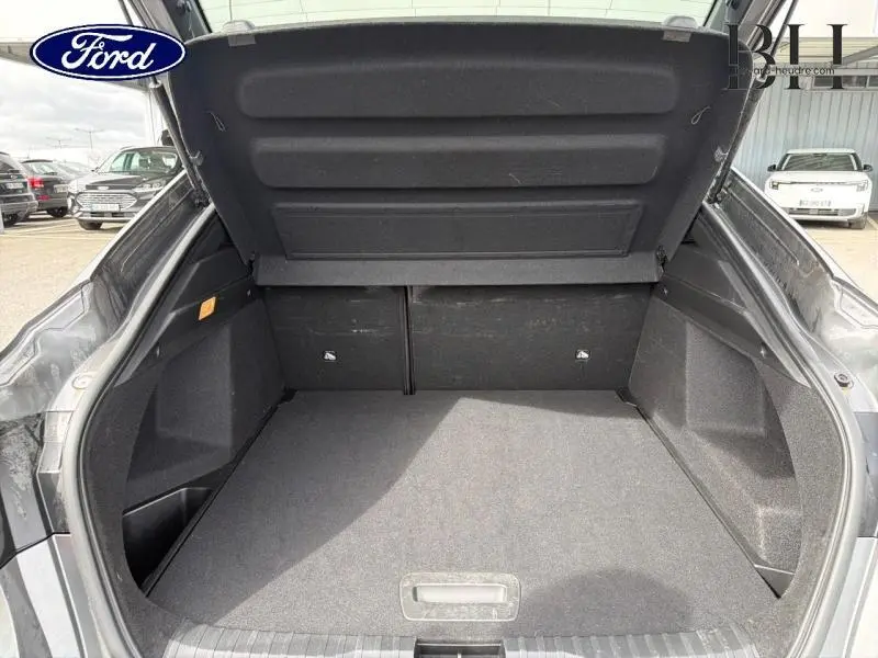 Coffre ouvert vu de l'arrière d'une Renault Arkana gris métallisé, espace de chargement vide et propre.